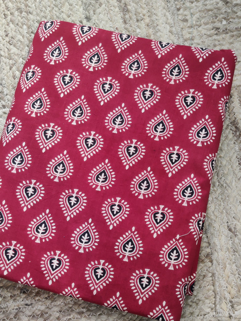 Red fabric with white and black pattern on a textured surface