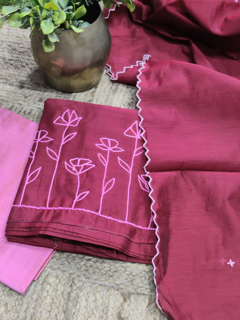 Maroon fabric with pink floral embroidery on a textured surface