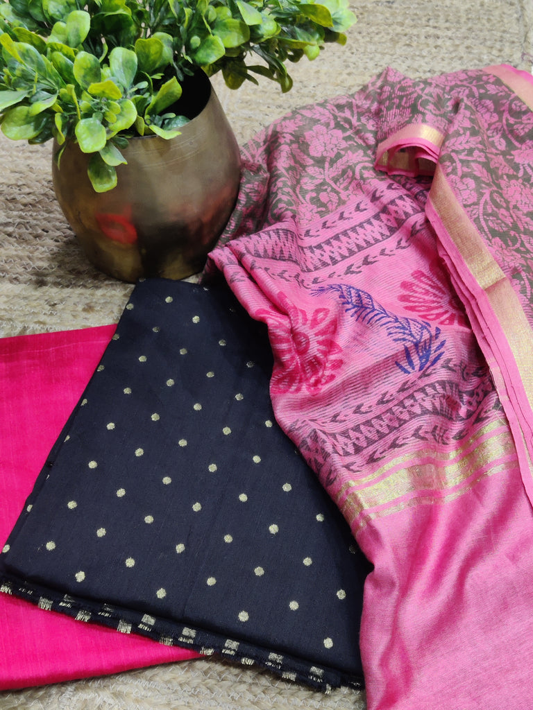 Pink fabric with intricate patterns next to a black and white polka dot fabric on a textured surface.