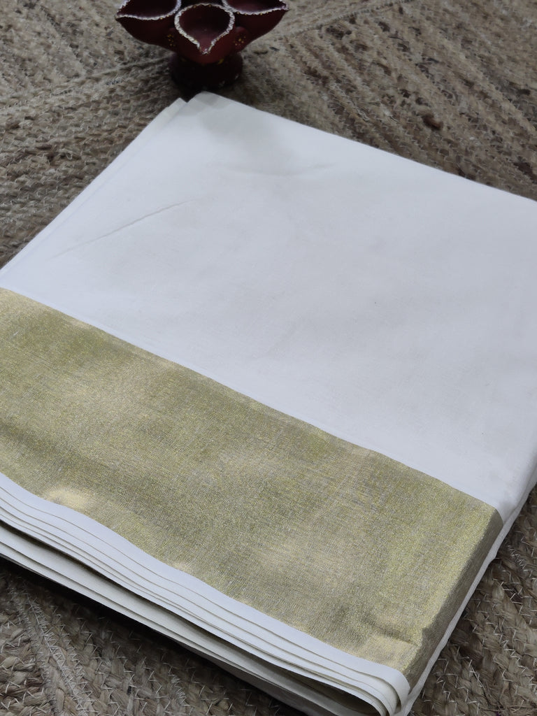 White fabric with a zari border on a textured surface