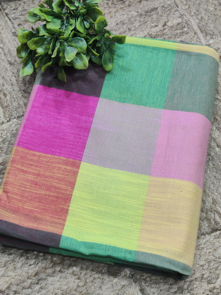 Colorful checkered fabric on a textured surface with green leaves.