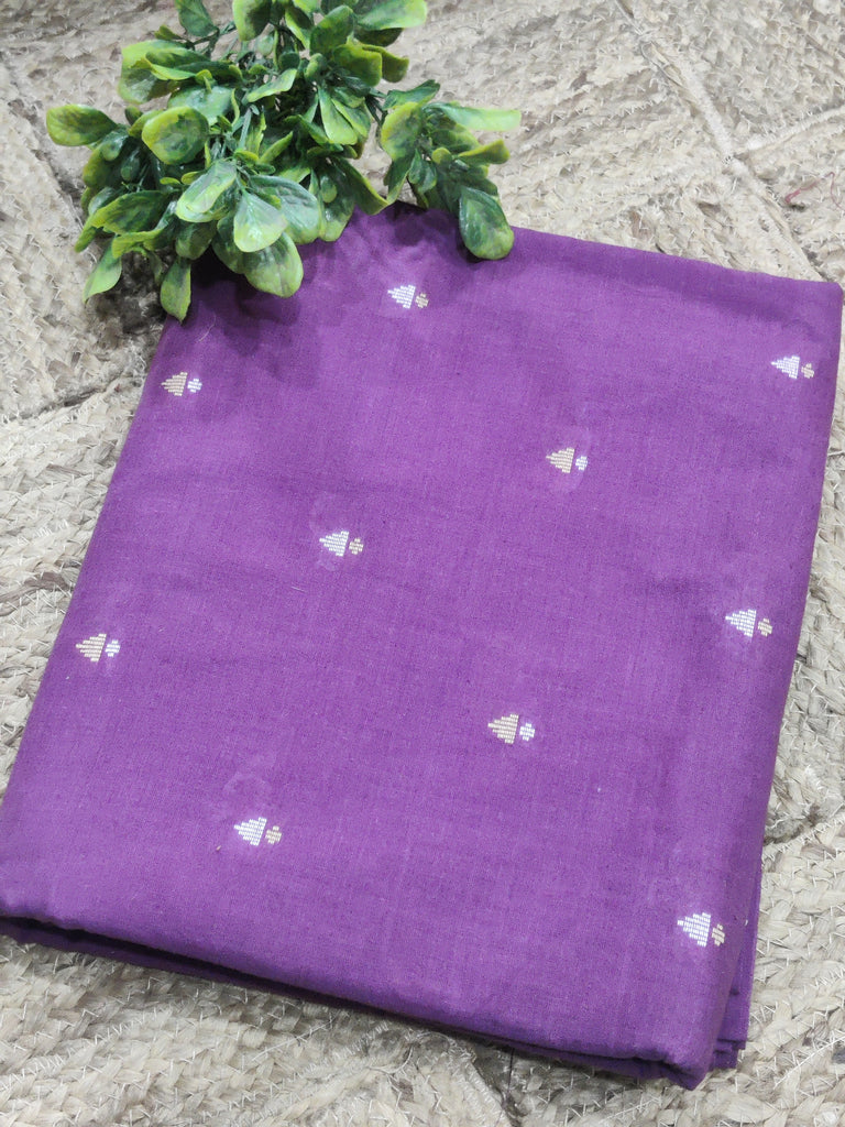 Purple fabric with white patterns on a stone surface with green leaves.