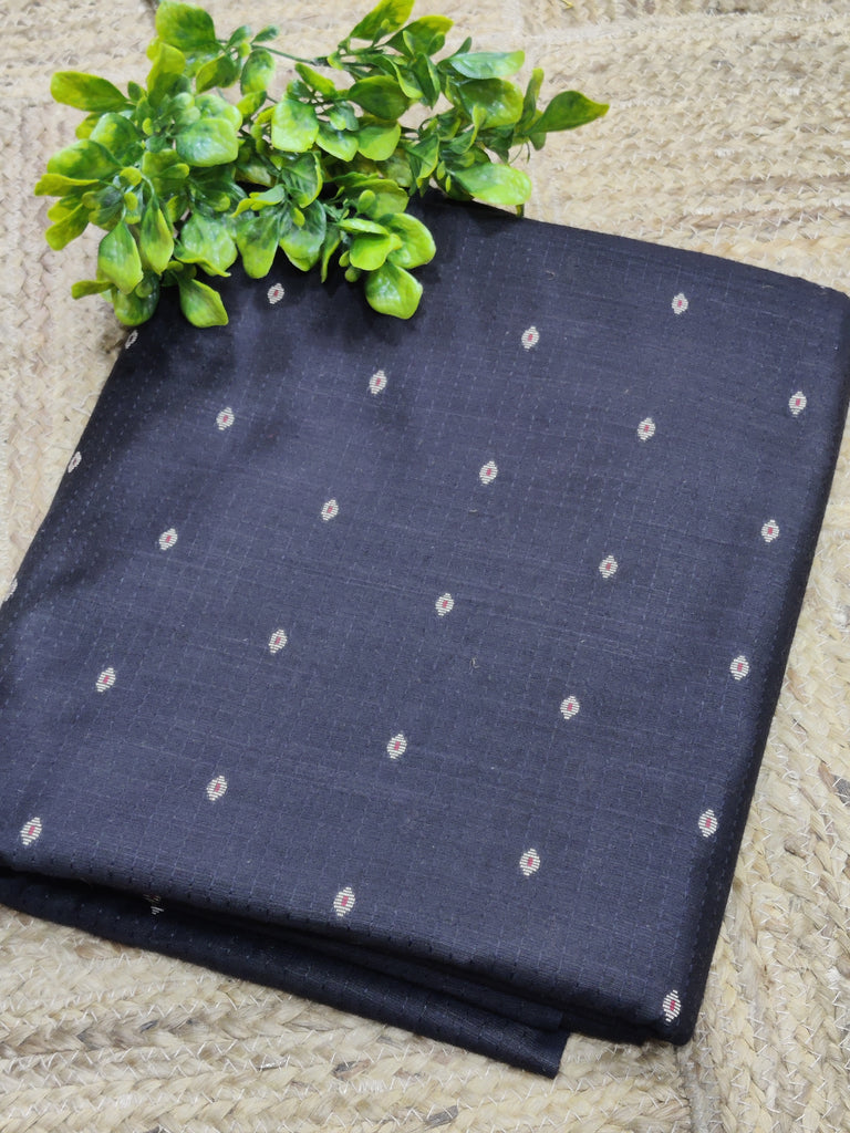 Folded dark blue fabric with white patterns on a textured surface with green leaves.