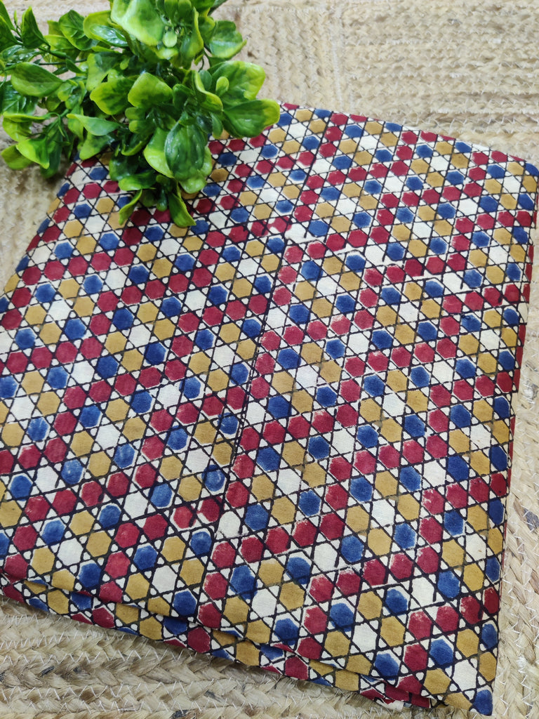 Colorful patterned fabric on a textured surface with green leaves.