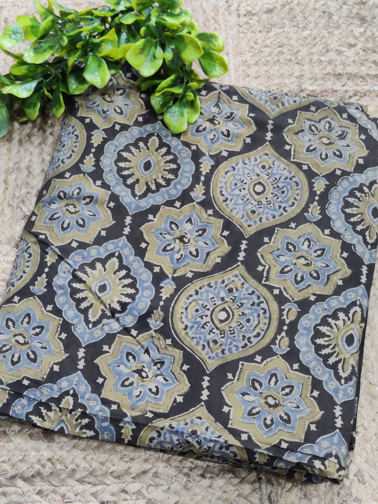 Decorative fabric with a pattern on a stone surface next to green leaves.