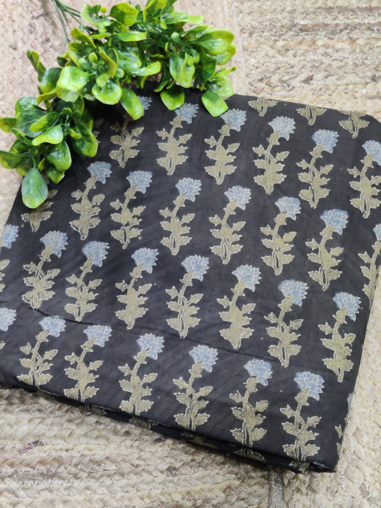 Floral-patterned fabric on a stone surface with green leaves.