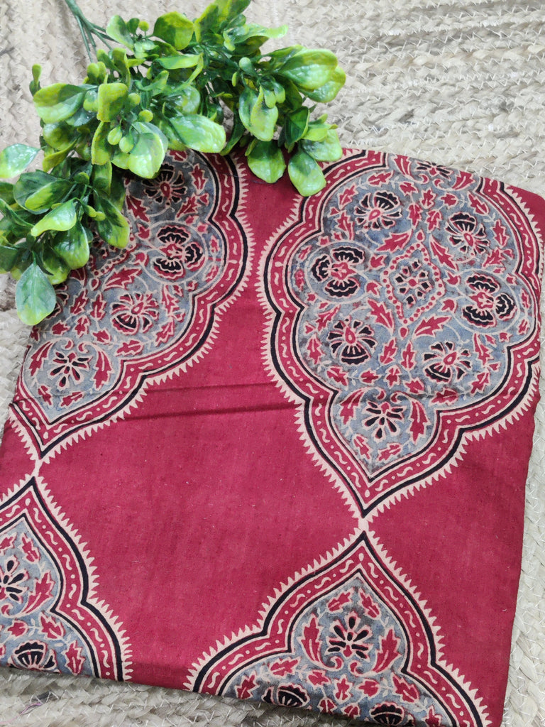 Red patterned fabric with green leaves on a stone surface