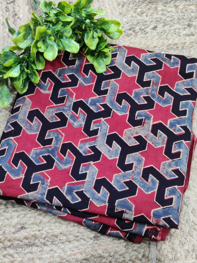 Folded fabric with geometric pattern on a textured surface with greenery