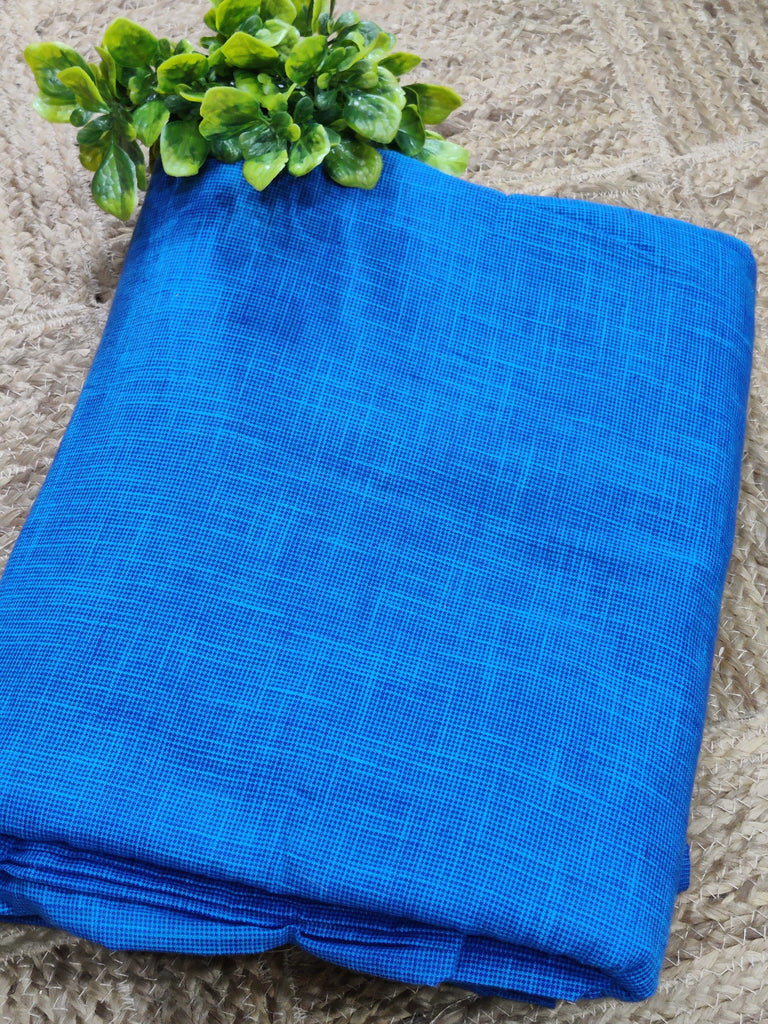 Folded blue fabric on a textured surface with green leaves.