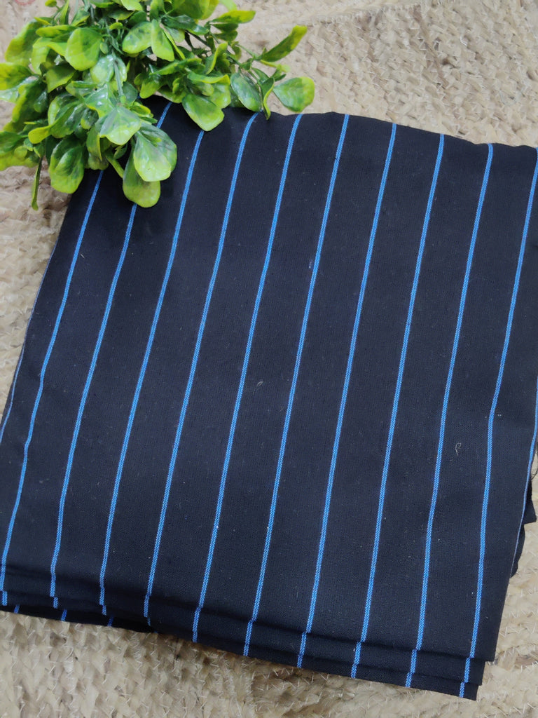 Folded fabric with blue pinstripes on a textured surface with green leaves.