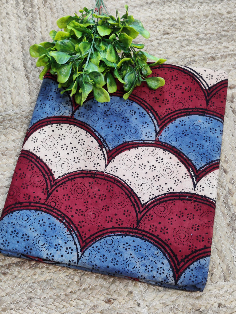 Decorative wall hanging with red, blue, and white pattern and green plant on a textured surface