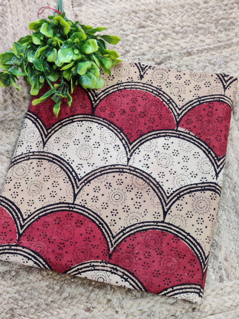 Decorative pillow with red, beige, and black pattern on a textured surface