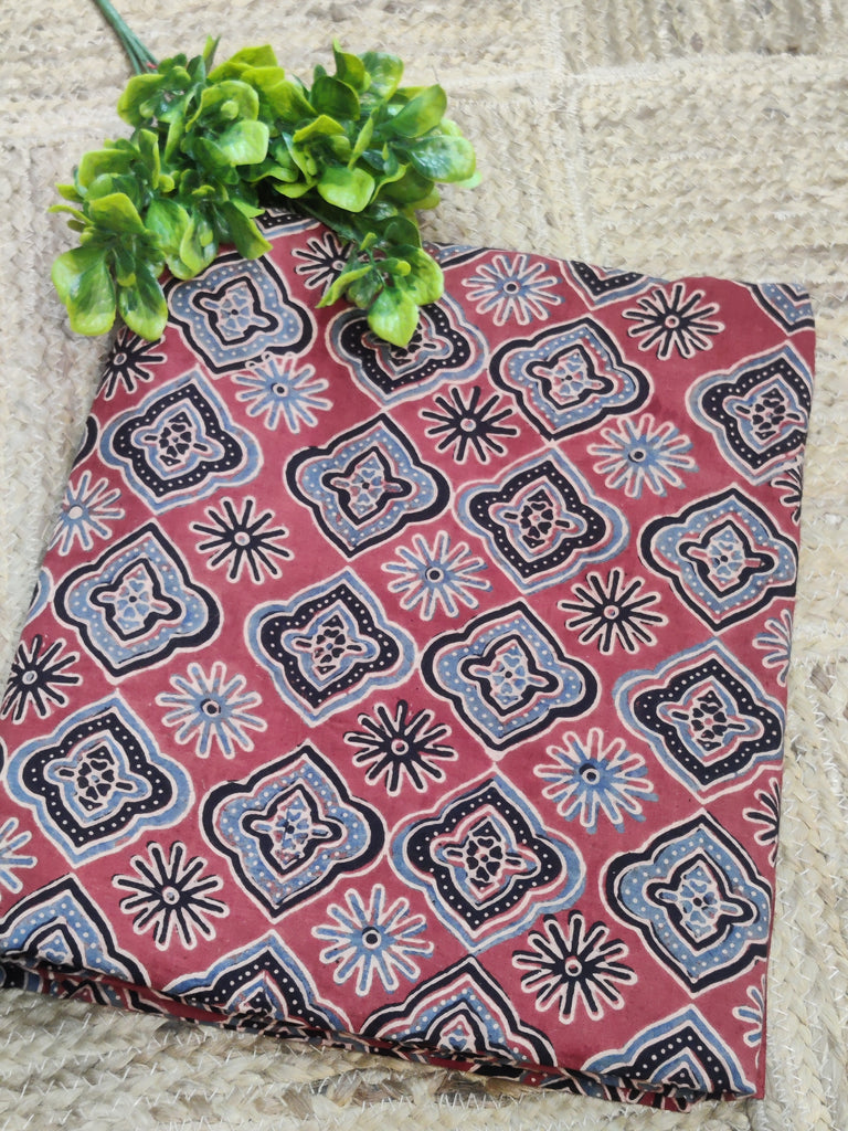 Fabric with a red and black pattern on a stone surface