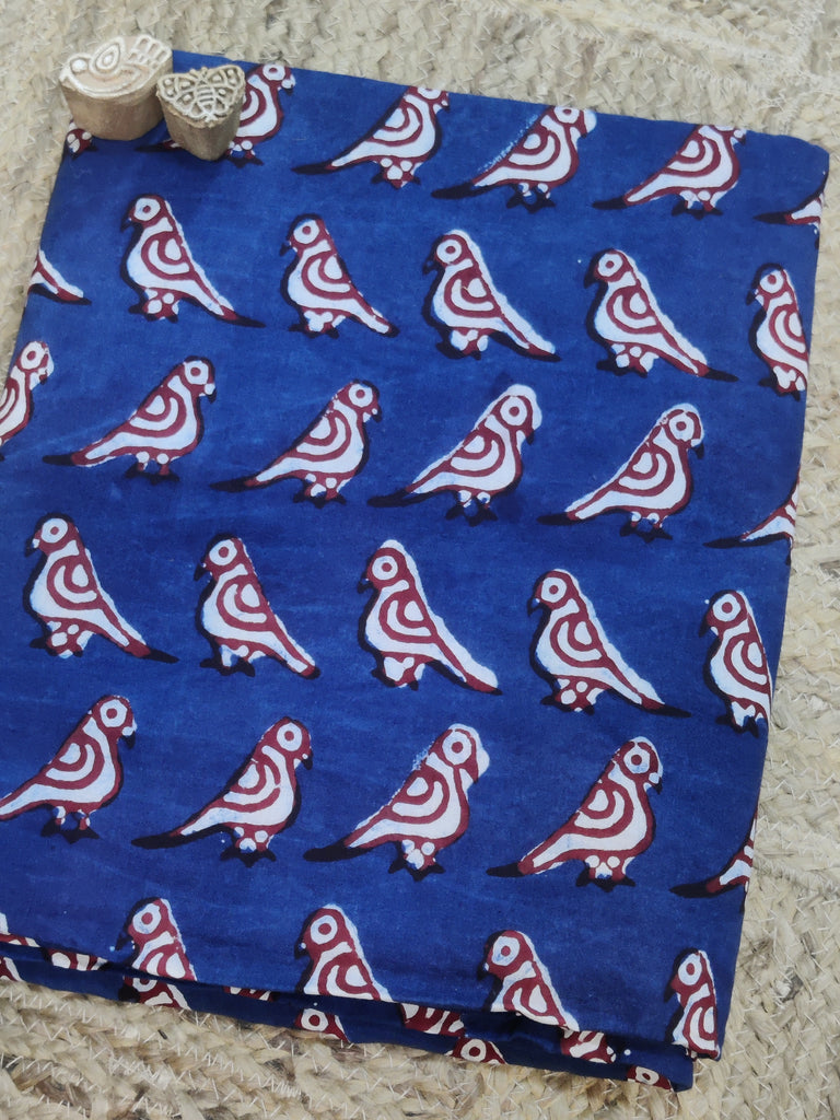 Blue fabric with red and white bird pattern on a textured surface